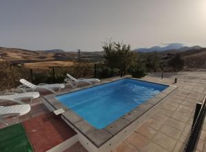 a swimming pool with two chairs and a table at Casa Rural Cerca Del Caminito Del Rey Ardales in Ardales