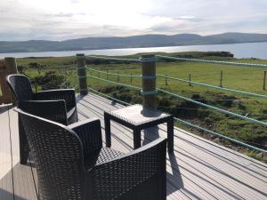 two chairs and a table on a deck with a view at Coral Cabins in Dunvegan