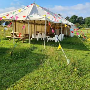 a tent with chairs and a table in a field at Bell tent glamping at Marwell Resort in Winchester