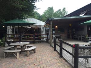 a patio with a table and benches and an umbrella at Bell tent glamping at Marwell Resort in Winchester