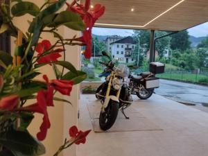 a motorcycle parked in a garage with red flowers at Hotel Da Marco in Vigo di Cadore