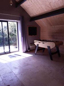 a ping pong table in a room with a window at Le Nid d'été in Montcléra