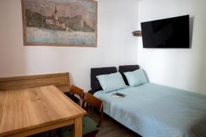 a room with a bed and a table and a tv at Apartmaji Utrinek, apartma Salon in Podbrdo