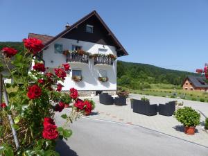 Um edifício com rosas vermelhas à frente. em House Pox em Plitvicka Jezera
