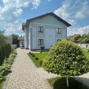 a white house with a brick driveway at Lebediny Guest House in Brest