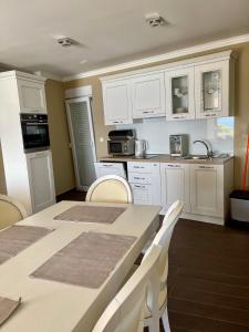 a kitchen with white cabinets and a table and chairs at Apartments Prestige in Petrcane