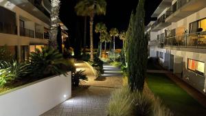 a courtyard of a building at night with palm trees at Cavalo Preto Luxury Beach Resort in Quarteira
