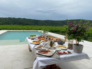 einen Tisch mit Teller mit Speisen neben einem Pool in der Unterkunft Casa Mulino - where the vineyards meet the sea in Sečovlje