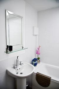 La salle de bains blanche est pourvue d'un lavabo et d'une baignoire. dans l'établissement 6 Bryn Terrace, Conwy, à Conwy