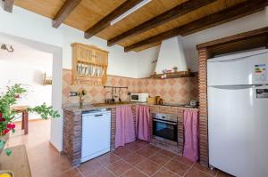 a kitchen with white appliances and pink towels at Cortijo Cabrilla in Periana