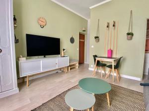 sala de estar con TV, mesa y sillas en We Sea, en Deauville