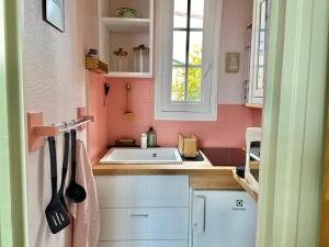 - une cuisine avec des murs roses et un évier blanc dans l'établissement We Sea, à Deauville