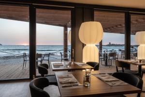 a restaurant with tables and chairs and a view of the ocean at Hotel Punta Tipa in Trapani