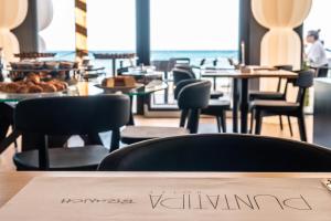 a restaurant with chairs and tables and a sign on a table at Hotel Punta Tipa in Trapani