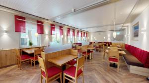 un restaurante con mesas de madera y sillas rojas en Hotel Rothenburger Hof en Rothenburg ob der Tauber