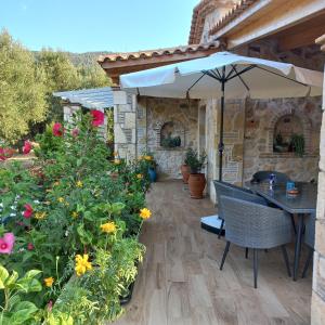 un patio con mesa, sombrilla y flores en Villa Liberta, en Kerion