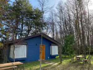 a blue cabin in the woods with a picnic table at Cabañas Dahue in Valdivia