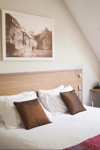 een bed met witte kussens en een foto aan de muur bij Hotel La Caleche in Durbuy