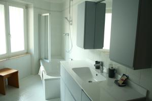 ein weißes Bad mit einem Waschbecken und einer Dusche in der Unterkunft le stanze di Saraswati in Salurn