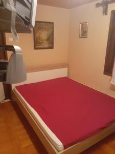 uma cama com um colchão vermelho num quarto em Zlatiborska seoska idila em Zlatibor