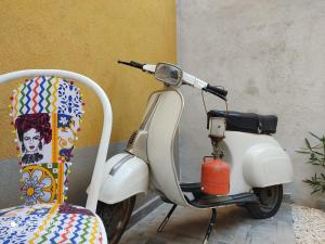 uma scooter branca estacionada ao lado de uma cadeira em Green House em Avola