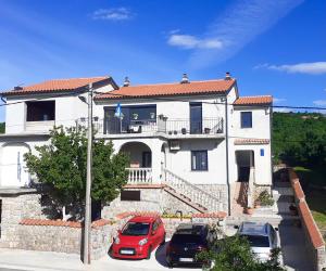 a large white house with cars parked in front of it at Apartments Maro in Senj