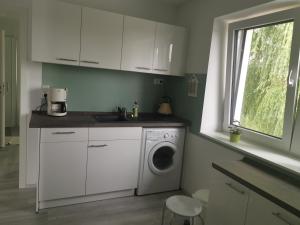 a white kitchen with a washing machine and a window at Thüringer Panorama in Gossel