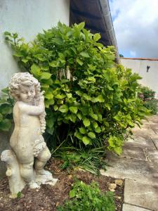 Una estatua de un angelito parado junto a un arbusto. en Chez Chris, en Jard-sur-Mer