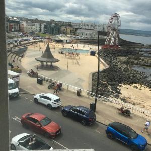 a group of cars parked on a street next to a beach at On The Prom in Portstewart