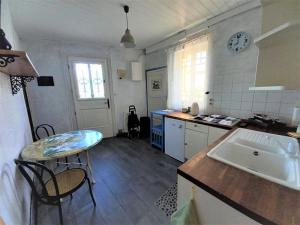 cocina con mesa, fregadero y encimera en Chez Chris, en Jard-sur-Mer