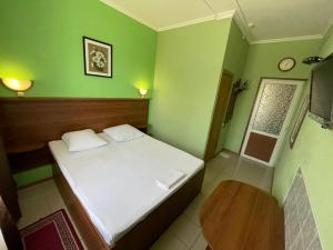 a small bedroom with a white bed and green walls at Гостиница Глория in Pyatigorsk