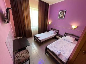 a small room with two beds and purple walls at Гостиница Глория in Pyatigorsk
