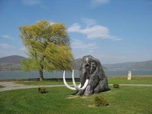 a statue of an elephant sitting in the grass at Milojković in Donji Milanovac