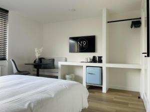 a white bedroom with a bed and a desk at N9 Texel in De Koog
