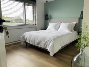 Schlafzimmer mit einem Bett mit weißer Bettwäsche und einem Fenster in der Unterkunft N9 Texel in De Koog