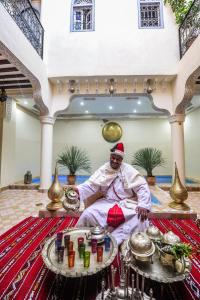 Ein Mann sitzt in einem Zimmer mit etwas Essen. in der Unterkunft Riad Milouda in Marrakesch