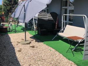 a patio with a chair and an umbrella and grass at Arenia Łeba -Filia Kompleksu ARENA SŁOŃCA in Łeba