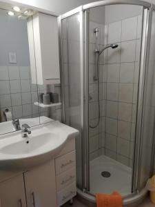 a white bathroom with a shower and a sink at Couple Appartement Pension Volgenandt in Breitenbach