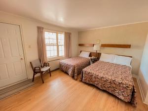 une chambre d'hôtel avec deux lits et une chaise dans l'établissement Silverwood Motel, à Cavendish
