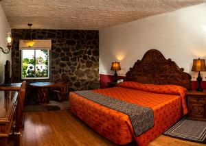 a bedroom with a bed with an orange bedspread at Posada de la Aldea in San Miguel de Allende