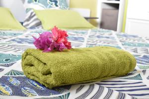 a green towel with a flower on top of a bed at Creole Nest in Pointe-Noire