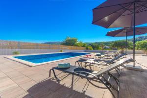 eine Gruppe von Stühlen und Sonnenschirmen neben einem Pool in der Unterkunft Villa Antonia with heated pool in Dograde