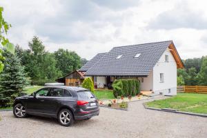 a black car parked in front of a white house at Dom Pod Gaikiem in Łękawica