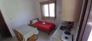 a small room with a red bed and a sink at Filio Rooms in Nikiti