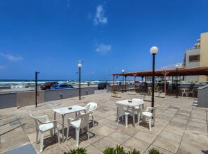 a patio with white tables and chairs and the ocean at Zantina in Rethymno