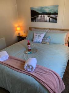 a bed with a towel and a bottle of wine on it at Bliss Beach Lodge in Bembridge