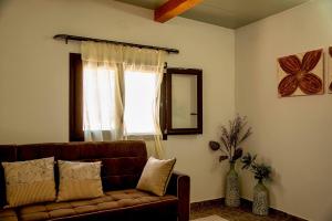 a living room with a brown couch and a window at flamingo colour valey house in Palekastron