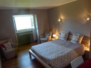 1 dormitorio con 1 cama, 2 sillas y ventana en Chambres d'Hôtes Baudelys, en Pont-de-Larn