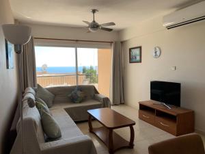 a living room with a couch and a flat screen tv at King's Palace - very spacious 1 bed apartment in Paphos
