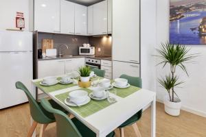 ポルトにあるD&S - Porto Theater Apartmentのキッチン(白いテーブル、緑の椅子付)